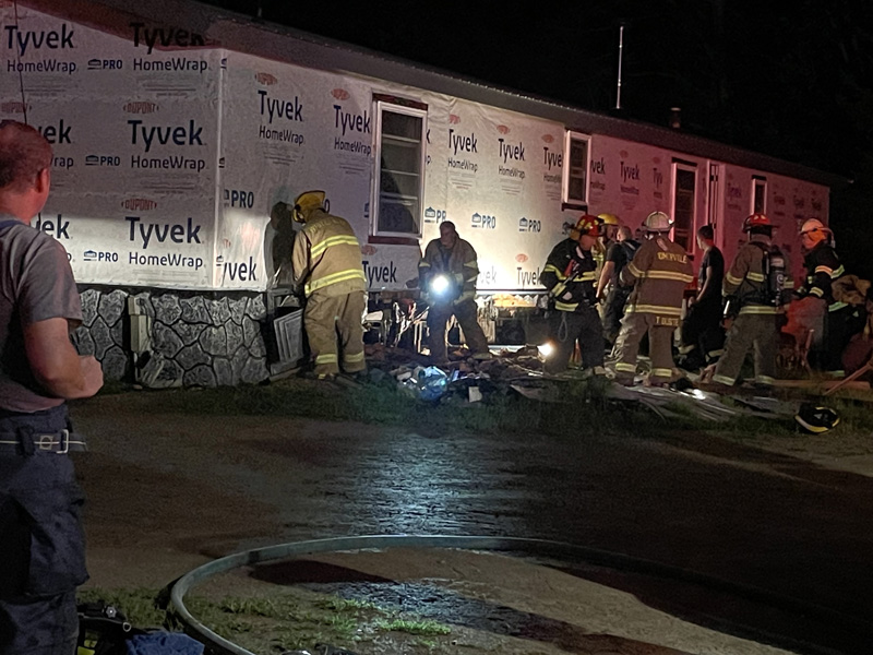 Fire fighters from six area departments peel away foundation material from a home on Hilton Road where a fire was reported Friday, Aug. 13. (Photo by Raye S. Leonard)