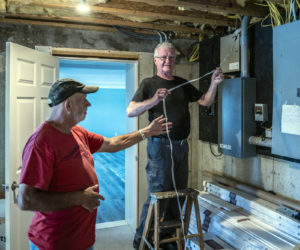 Sam Hafford and Ernie Carroll feed a length of tape from inside a basement through to the exterior of a home in Bremen on Tuesday, Sept. 7. (Bisi Cameron Yee photo)
