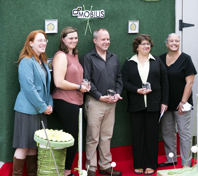 From left: Rebecca "Becca" Emmons, Emily Huber, Claude Elliott, Cathi Laweryson, and Michaela York pose for photos on an impromptu red carpet at Mobius Inc., in Damariscotta on Sept. 22. The large spool of thread represents the theme of "the threads we weave" that speaks to Mobius' integration into the communities of Lincoln County. (Bisi Cameron Yee photo)