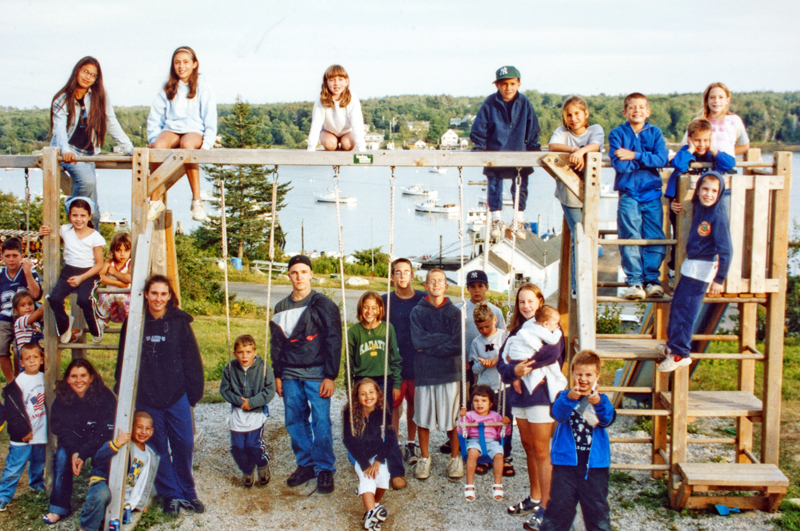 Campers pose for a group photo on a swingset at the Pemaquid Fishermen's Coop during the first 9/11 Famiily Camp at Camp Kieve in 2002. (Photo courtesy Kieve Wavus Education)