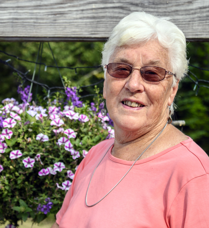 Donna Plummer stands with some of the flowers on her porch in South Bristol on Wednesday, Aug. 25. Plummer said her favorite flower is the star gazer lily, for it's lovely name and its sweet scent. (Bisi Cameron Yee photo)