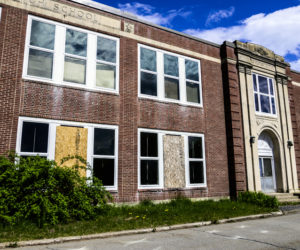 Boards cover broken windows on the front of the A.D. Gray building in Waldoboro on May 14. The brick facade that covers the building has been deemed unstable and the building may need to be demolished. (Bisi Cameron Yee photo, LCN file)