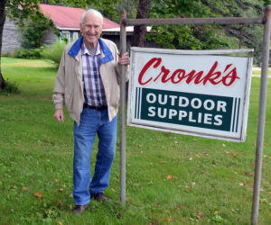 Oscar Cronk stands by his sign on the Gardner Road. "Cronk's Outdoor Supplies" will be coming down since he recently sold the business, and announced he will retire after nearly 60 years. (Charlotte Boynton photo)