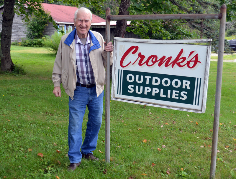 Oscar Cronk stands by his sign on the Gardner Road. "Cronk's Outdoor Supplies" will be coming down since he recently sold the business, and announced he will retire after nearly 60 years. (Charlotte Boynton photo)