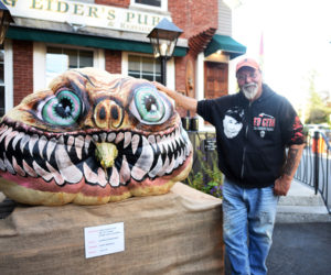 Newcastle artist Glenn Chadbourne stands next to his pumpkin monster in front of King Eider's Pub in Damariscotta in October 2018. (LCN file photo)