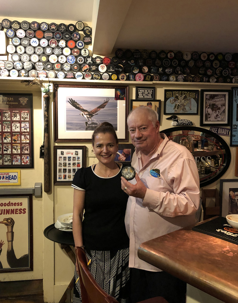 Bobby Whear stands with Tamara Dica, co-owner of the Damariscotta River Grill, holding a recently acquired hockey puck signed by Pittsburgh Penguins player Sidney Crosby in June 2019. Whear tends bar one or two nights a week at the grill, where he is extremely proud of his hockey puck collection, which consists of over 300 pucks from around the world. (Evan Houk photo, LCN file)