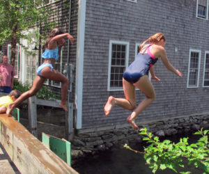 Grandkids in mid-air leaping off the bridge in the Mills.