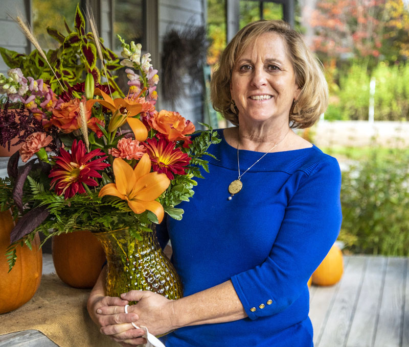 Shelley Pease holds a bouquet of fall flowers in front of her shop in Waldoboro. Pease has owned Shelley's Flowers & Gifts for 39 years. (Bisi Cameron Yee photo)
