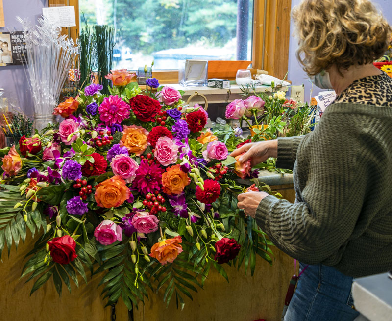 Shelley Pease puts the finishing touches on a memorial display at her shop. (Bisi Cameron Yee photo)
