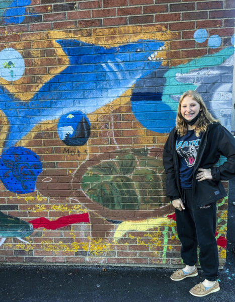 Bailey Lash poses in front of the green sea turtle she painted for the ecoarts mural at Medomak Valley High School in Waldoboro. (Photo courtesy Krisanne Baker)