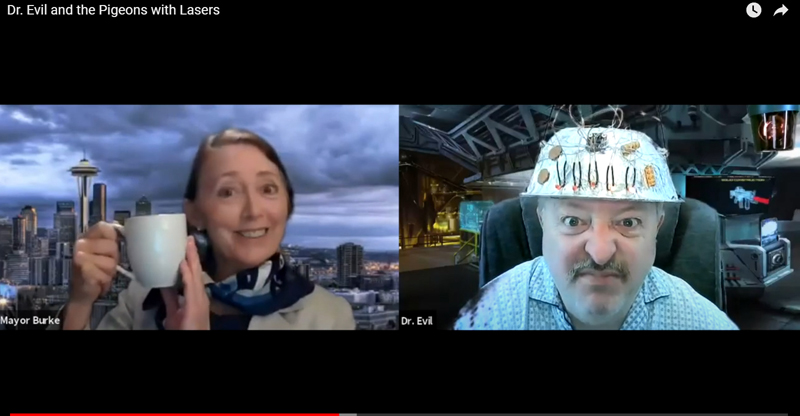 Christine Tupper as the mayor of Seattle does not appear worried by Mitchell Wellman as Dr Evil's scheme to threaten the coffee supply in the River Company's production of "Dr. Evil and the Pigeons with Lasers." (screenshot)