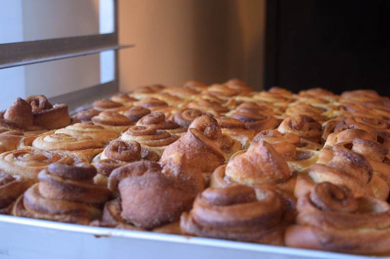 The Cupboard Cafe's famous cinnamon buns cool on a rack as Jennifer Leeman and Mary Dee Grant prepare to mail them out to customers on Dec. 12. (Nate Poole photo)