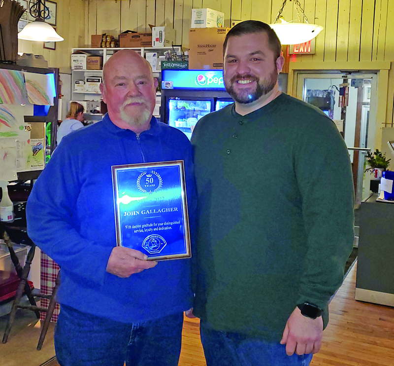 John Gallagher is presented a plaque to commemorate his 50 years of service to Central Lincoln County Ambulance Service by Service Chief Nicholas Bryant. Bryant made the presentation to Gallagher at the services annual dinner held Dec. 8 at Reunion Station in Damariscotta. Gallagher has the longest service record of anyone in the history of the service. (Courtesy photo)