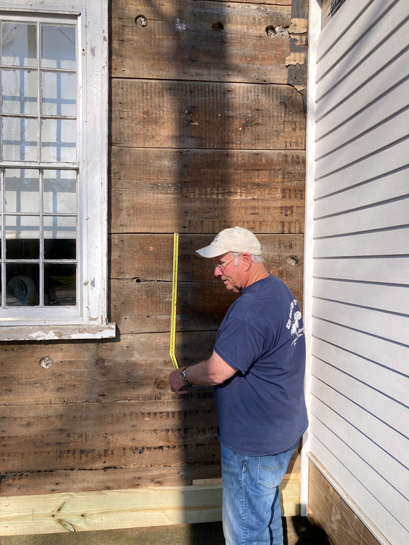Danny Day measures original boards on the house built by his many times great grandfather. (Contributed photo)