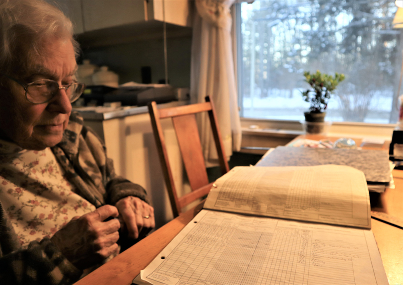 Newcastle resident Arlene Cole reviews her recent temperature and precipitation recordings at the kitchen table of her home. (Emily Hayes photo)