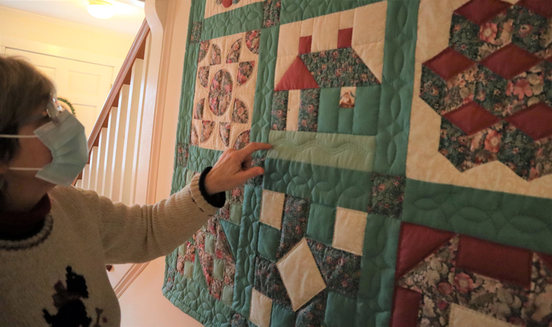 Barbara Higgins admires her mother's homemade quilt on the wall of Eleanor Smith's home in Waldoboro. (Emily Hayes photo)