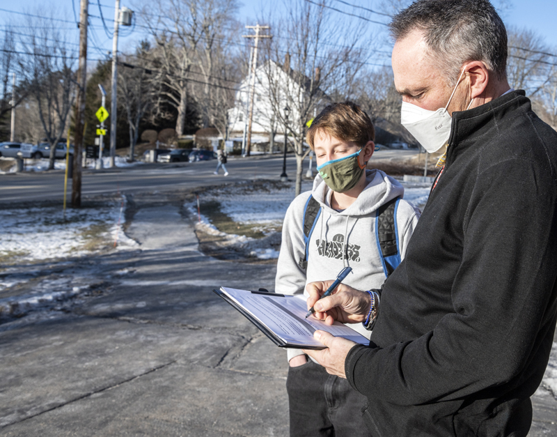 Roan Donaghy observes as Lincoln Academy Head of School Jeffrey Burroughs signs his skate park petition in Newcastle on Jan. 11. Burroughs supports the park as a place where kids can "be together in a constructive way. " (Bisi Cameron Yee photo)