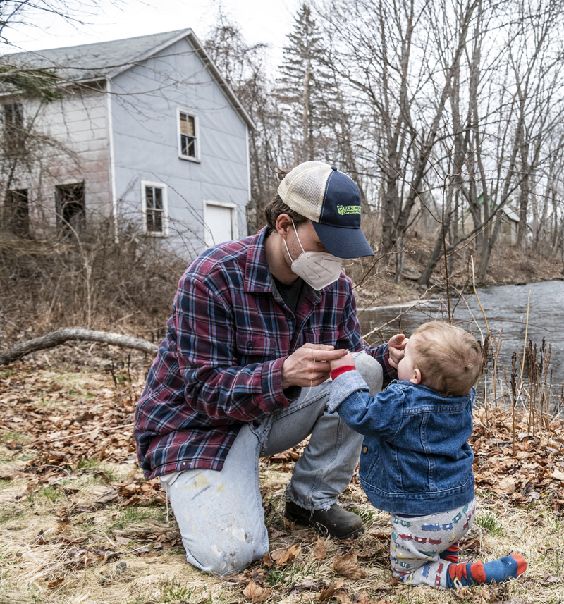 Russell Brackett plays with son Fletcher on the banks of the Penobscot River behind their home in Bristol. (Bisi Cameron Yee photo, LCN file)