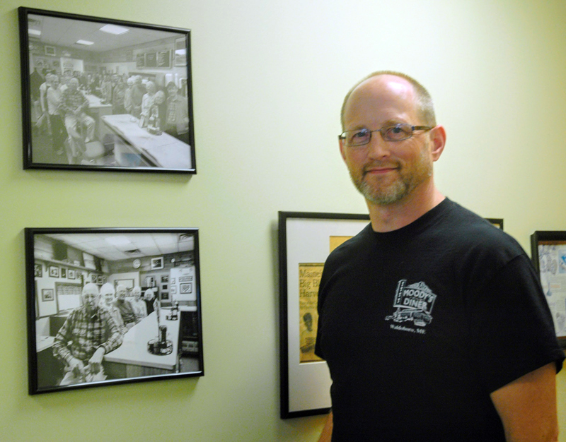Moody's Diner co-owner Dan Beck, a grandson of founders Percy and Bertha Moody, stands next to photographs of the family at the diner in 2017. (LCN file photo)