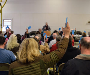 Alna citizens raise their cards Moderator Jim Lothridge calls for a vote at the annual town meeting on March 26. (Nate Poole photo)