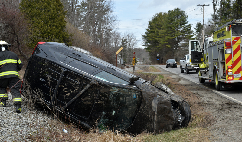 A Newcastle firefighter examines the scene of a single-vehicle rollover on Mills Road in Newcastle on Tuesday, April 12. The driver of the black Toyota RAV-4 was not injured. (Evan Houk photo)