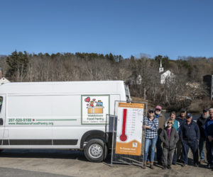 From left: Natalie Masse, Jeff Brown, Janet Lee, Nancy Lippert, Bill Blodgett, Lenny Ryan, Meyer Drapkin, Dale Turner, and Jan Visser stand for a photo with the Waldoboro Food Pantry's new van beside them and the town they serve behind them in Waldoboro on April 4. (Bisi Cameron Yee photo)