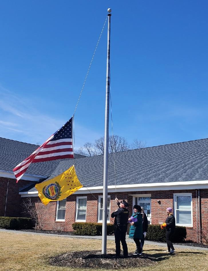 Wiscasset Police Chief Larry Hesseltine raises the Vietnam veterans memorial flag outside of the town office on March 29. (Courtesy photo)