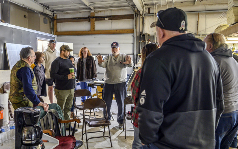Ed Harmon (center), founder of Boothbay V.E.T.S, gives volunteers from the Togus Regional Office the lay of the land during a work session to build trailers for homeless veterans in Boothbay on April 30. Togus is a medical facility operated by the U.S. Department of Veterans Affairs in Chelsea. (Bisi Cameron Yee photo)