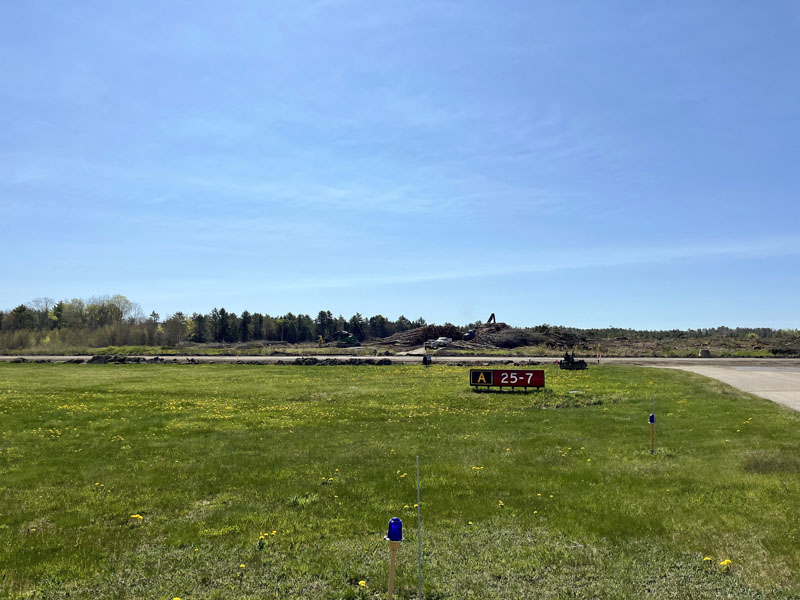 Behind Wiscasset Municipal Airport's runway, timber is stacked where a solar-energy array will go. Construction on the runway should be complete by July 1. (Anna M. Drzewiecki photo)