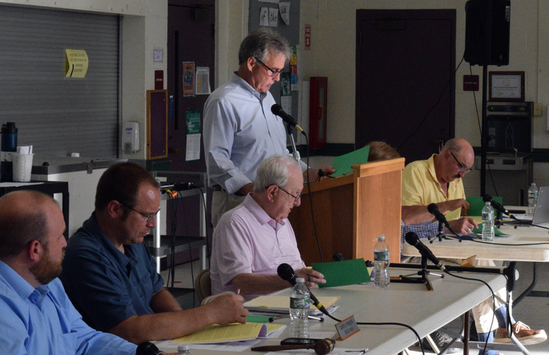 Moderator Jim Cosgrove reads a warrant article during the open portion of Damariscotta's annual town meeting as the Damariscotta Select Board looks on at Great Salt Bay Community School on Wednesday, June 15. All articles were approved with no discussion and all the referendum articles from annual town meeting were approved at the polls the day before. (Evan Houk photo)