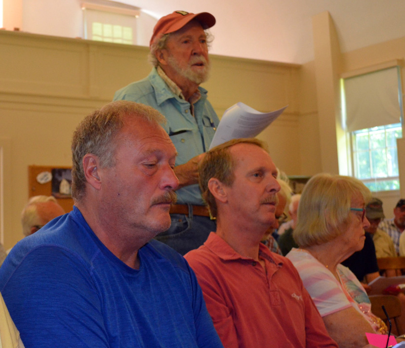 Westport Island resident E. Davies Allan stands and makes a motion to amend a warrant article at the town's annual town meeting on Saturday, June 25. Seated in front of Allan is the family of retiring First Selectman George Richardson  his sons Chuck and Garry and wife Marcia. (Charlotte Boynton Photo)