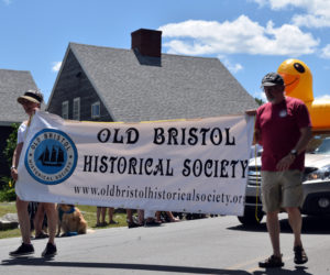 Brenda Osier and Chuck Rand hold a banner for the Old Bristol Historical Society during the Round Pond Fourth of July parade. The giant inflatable duck is raising awareness for the Ducky Boat Races fundraiser, which will be held at 1 p.m. on Sunday, Aug. 21. (Evan Houk photo)