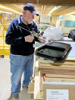 Ed Harmon primes a window for installation at his workshop in Boothbay. (Photo courtesy Boothbay V.E.T.S. Inc.)