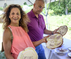 Jan Tessein holds up two plate possibilities while husband Ernie considers yet another option during Salad Days at Watershed Center for the Ceramic Arts in Newcastle on Saturday, July 9. Their daughter, Grace, is the Salad Days artist-in-residence. (Bisi Cameron Yee photo)