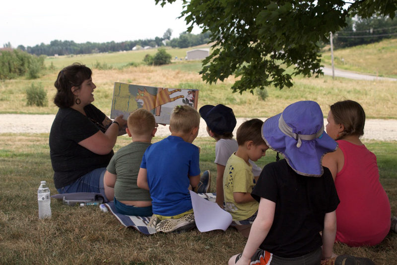 Emma Nelson read to Whitefield Library story time attendees at during a field trip to Sheepscot Valley Farm on July 18. (Iris Pope photo)