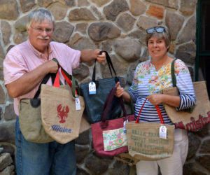 Blue Earth Bags owners Rusty and Kim Fenn hold up a variety of bags they made out of recycled materials. (Paula Roberts photo)