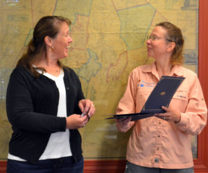 Lincoln County Communications Director Tara Doe (right) presents dispatcher Anita Sprague with a Stork Award at the Lincoln County Board of Commissioners meeting on Tuesday, Aug. 16. On June 13, Sprague successfully helped deliver a baby girl by telephone before emergency medical services arrived on scene. (Charlotte Boynton photo)