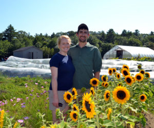 Kelsey Gibbs and Matt Silverman stand among sunflowers at Wanderwood, their sustainable stays and events business and organic farm at 79 Sidelinger Road in Nobleboro. The couple purchased the property in May 2017. (Maia Zewert photo)