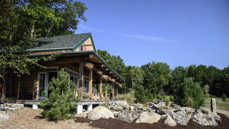 A parade home emerges from the forested section of a property in Waldoboro on Aug. 21. The home was designed to exist in concert with the land it is built on, making use of the natural resources of wood and stone found on the lot. (Bisi Cameron Yee photo)