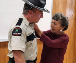 Joanne Maddox pins the District Forest Ranger emblem on her son, Scott Maddox, at a recent swearing-in ceremony. (Photo courtesy Maine Forest Service)
