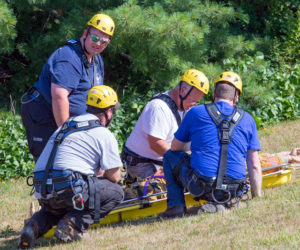 Firefighters from the Damariscotta and Waldoboro fire departments participate in a low-angle rescue exercise. A dummy is strapped into basket for retrieval through the use of a rope system anchored at the top of the hill. (Photo courtesy Kyle Santheson)