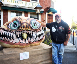 Newcastle artist Glenn Chadbourne stands next to his pumpkin monster in front of King Eider's Pub in Damariscotta in October 2018. (LCN file)