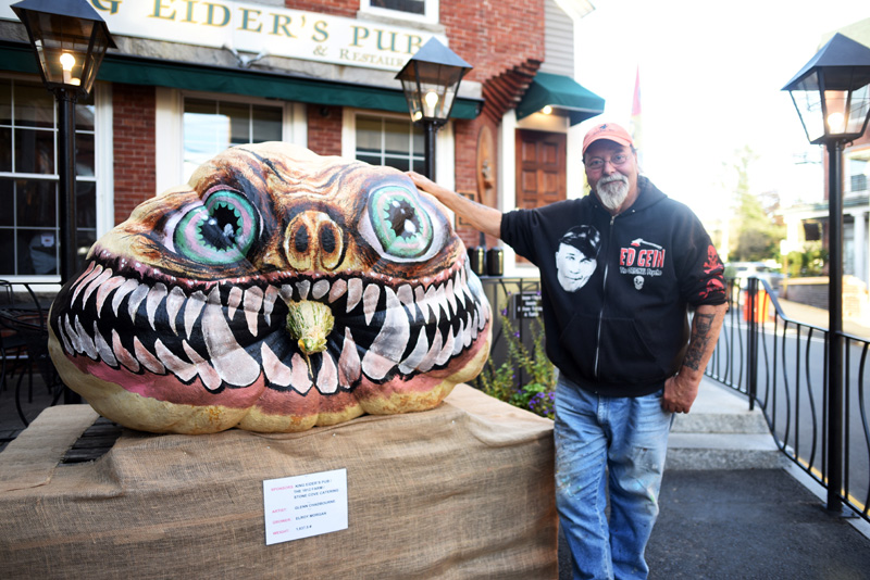 Newcastle artist Glenn Chadbourne stands next to his pumpkin monster in front of King Eider's Pub in Damariscotta in October 2018. (LCN file)
