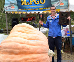 Charlie Lopresti, WGME chief meteorologist and master of ceremonies for the Damariscotta Pumpkinfest & Regatta weigh-off, stands in front of his first place 2,080-pound giant pumpkin after the event on Sunday, Oct. 2. The average weight of the top 10 giant pumpkins was 1,547 pounds, up from last year, according to Pumpkinfest co-founder Bill Clark. (Evan Houk photo)