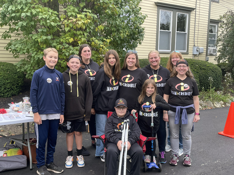 Ian Michaud (seated) is flanked by family and friends who came together to organize the Ian-credible Mega Multi Family Yard Sale on his behalf Saturday, Oct. 1. Ian Michaud, 10, has been diagnosed with a rare type of bone cancer and is currently undergoing treatment. From the left Jasper Pennman, Mason Davis, Jenn Caron, Sofia Michaud, Kristen Michaud, Evelyn Michaud, Rosie Davis, Amanda Swanberg, and Debra Lomas. (Sherwood Olin photo)