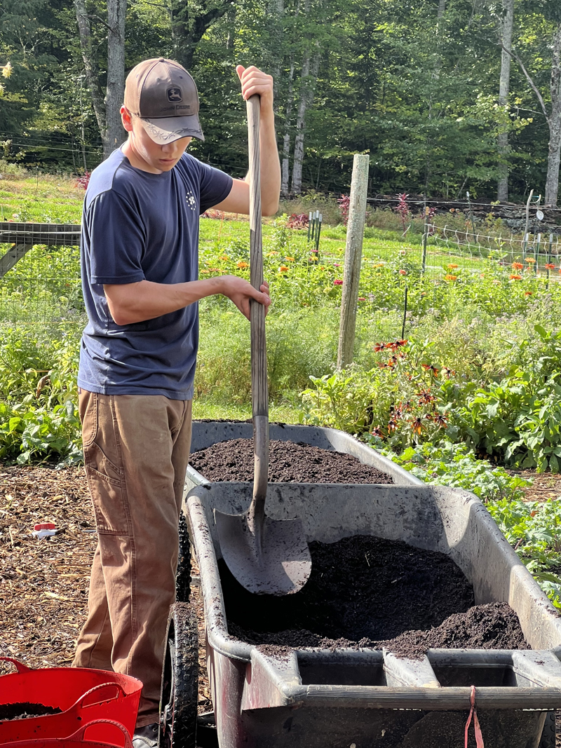 Lincoln Academy Sophomore Kaiden Abbott working with compost at Veggies to Table Farm in Newcastle. (Photo courtesy Lincoln Academy)