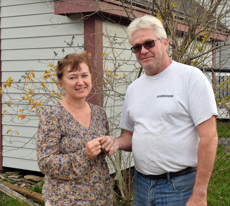 Jeff Pierce hands off a 1958 Bridge Academy class ring that is suspected to have belonged to Hazel Moody to Hazel's daughter-in-law, Sherry Moody, at his Dresden home on Nov. 1. Pierce found the ring by chance underneath a lilac bush after moving the bush several times during renovations. (Evan Houk photo)