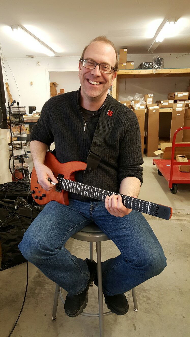 Newcastle native Corey Redonnett plays a prototype electric guitar in the NS Design office in Nobleboro. Redonnett has worked for the pioneering Nobleboro business in various roles since 2007. The guitar is based on the extremely successful line of the NS Design Radius electric bass guitars the company introduced in 2013. (Photo courtesy Corey Redonnett)