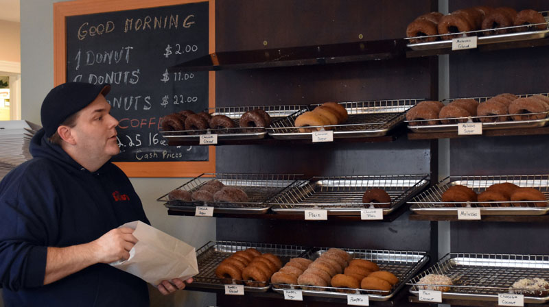 Old Time Donuts owner Mark Abruzese bags a customer's choices on Saturday, Dec. 31. The store make between 400 and 500 donuts fresh every morning. (Elizabeth Walztoni photo)