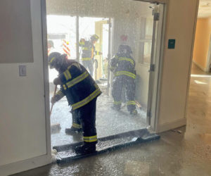 A firefighter cleans up the mess after a water line burst in the Lincoln Academy's Hall House over the weekened. The damage forced the school to close for two days this week. (Photo courtesy Lincoln Academy)